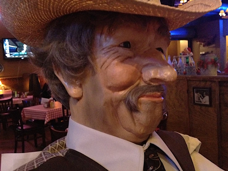 a man wearing a straw hat and vest blowing his nose