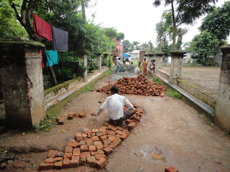 people on dirt with a pile of bricks