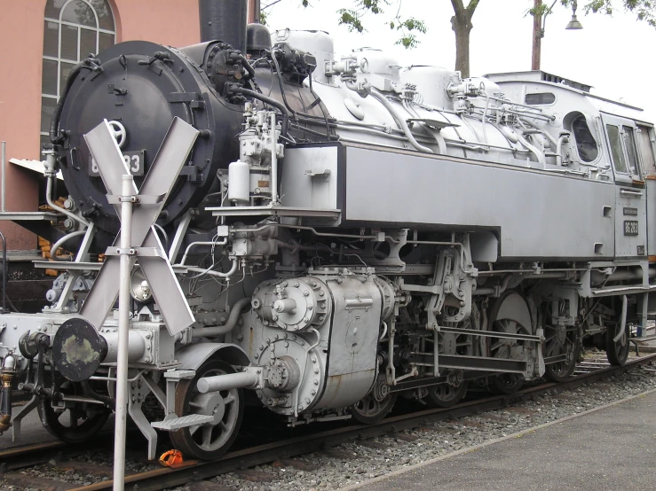 an old train engine with steam from the front sits on the tracks