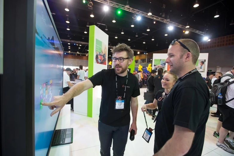 two men standing in front of a large screen display