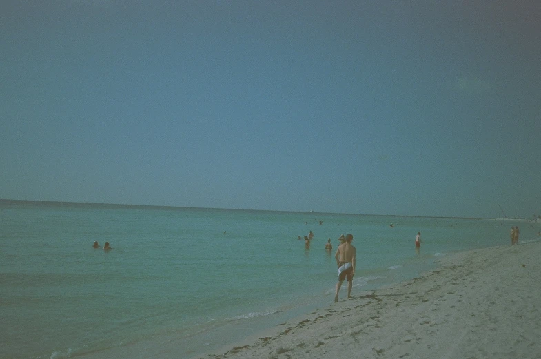 a group of people standing on the edge of a beach