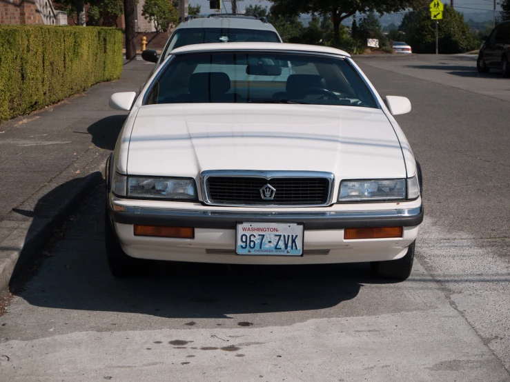 a car parked on the side of a road near a hedge