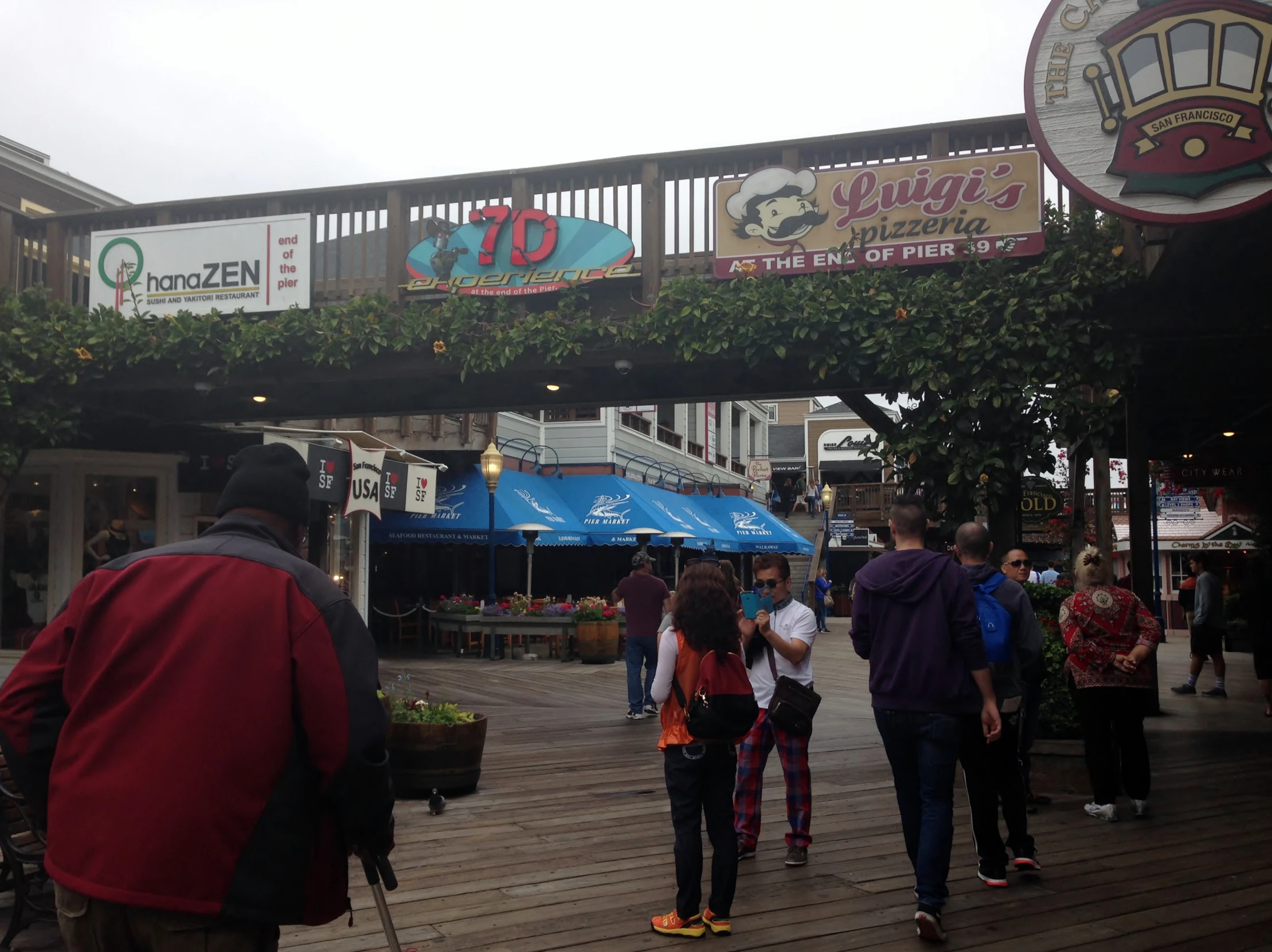 people walking around an outside market with many signs