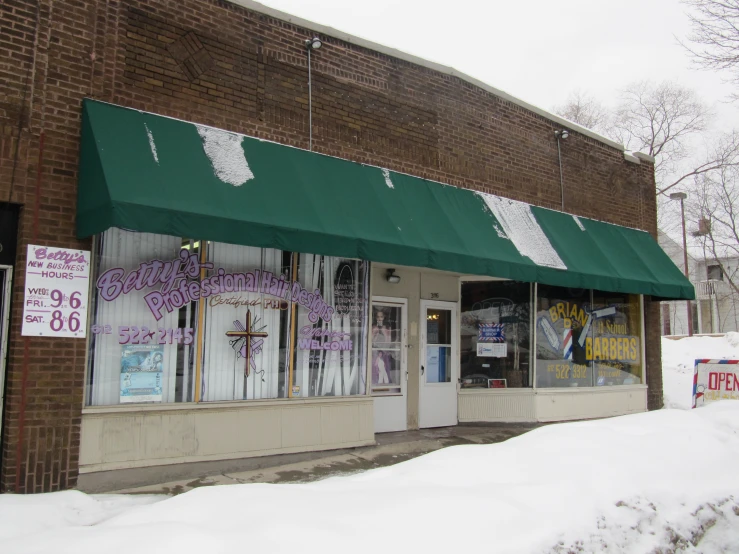 a store front with a green awning and white trim