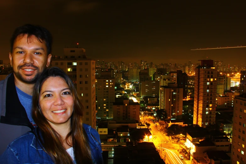 a man and woman smile in front of the city skyline