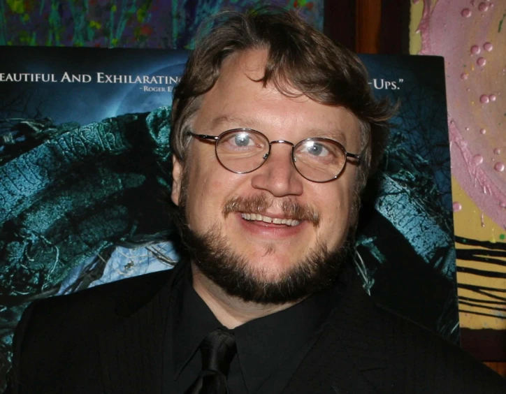 a man in glasses and a suit smiles for the camera