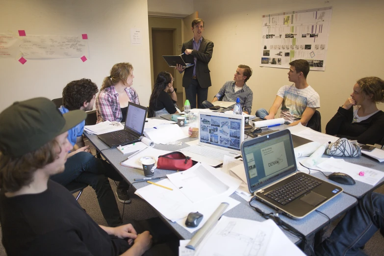 a group of people sitting around a table in front of laptop computers