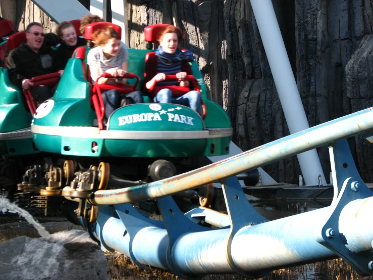 children riding a green park roller coaster