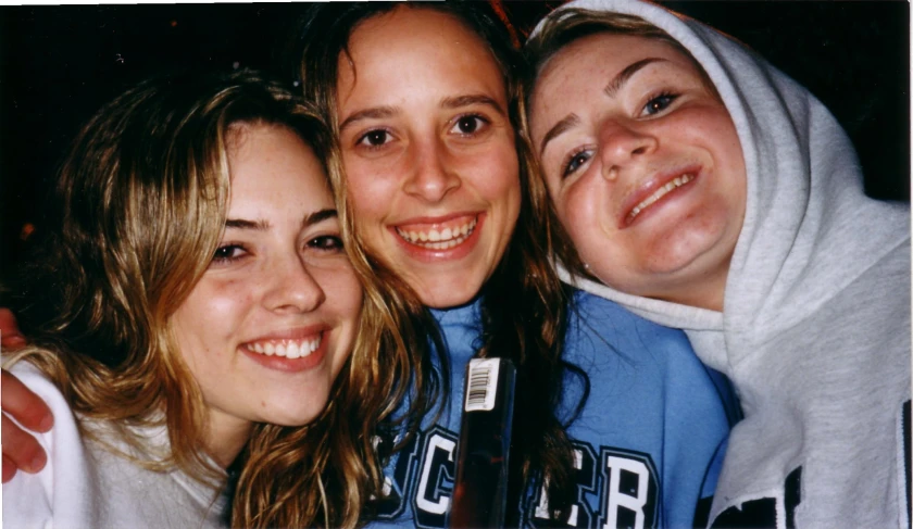 three girls standing together and smiling for the camera