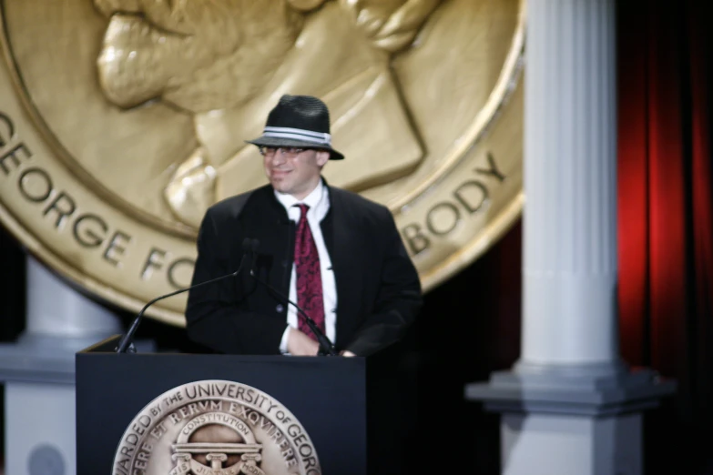 a man wearing a suit and tie standing behind a podium