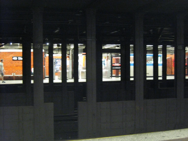 train passing through subway station at night with people walking on the platform