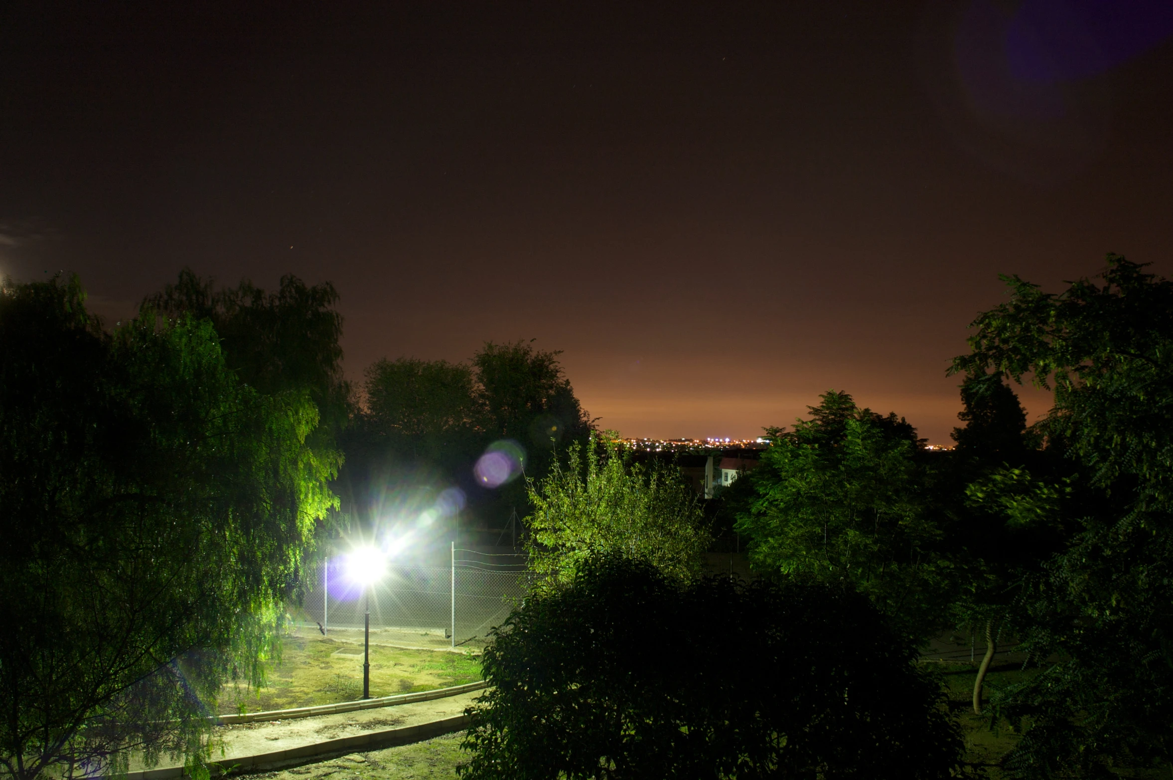 lights shine at night on the side of a grassy area