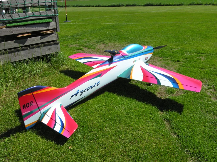 a plane painted bright sitting on the grass in the sun