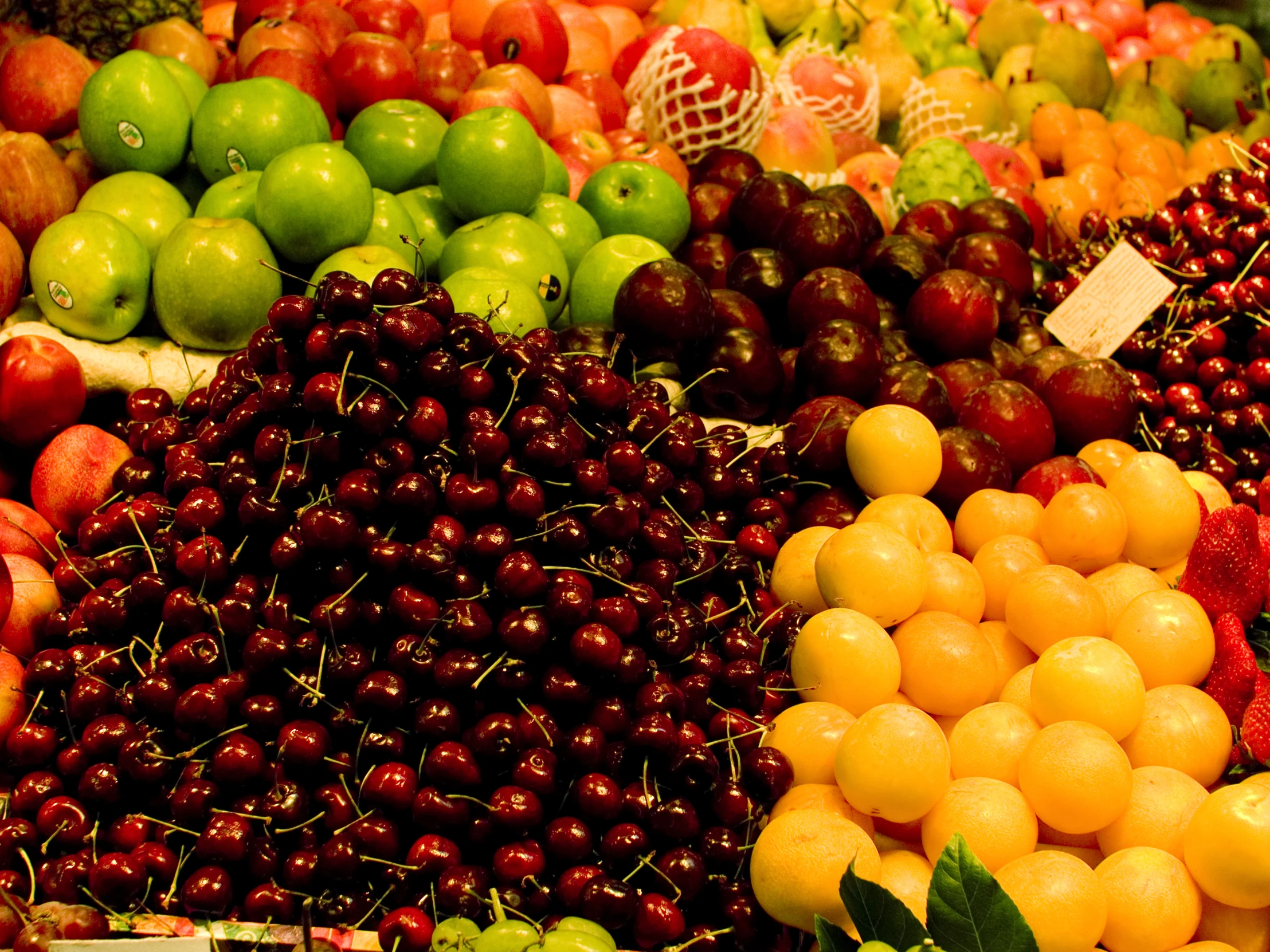 apples, oranges and other assorted fruit are displayed