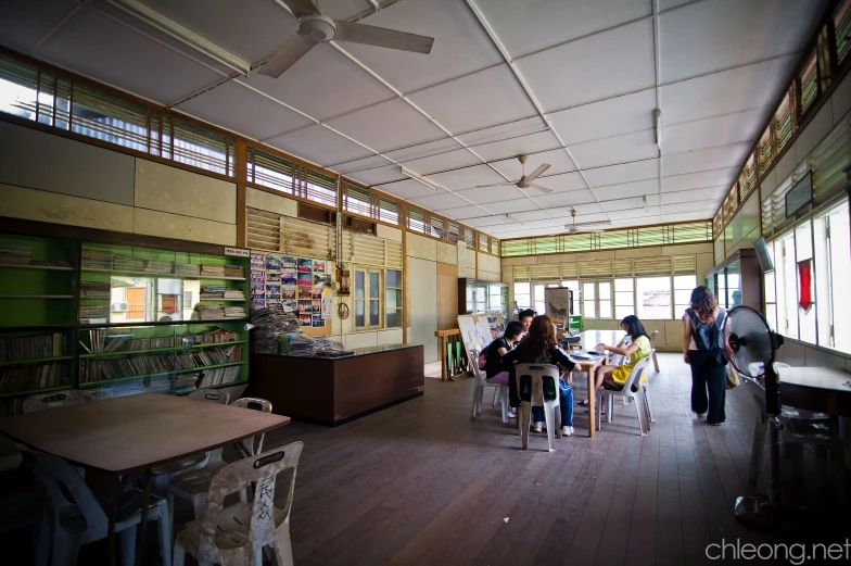 a dining hall with windows and people at tables