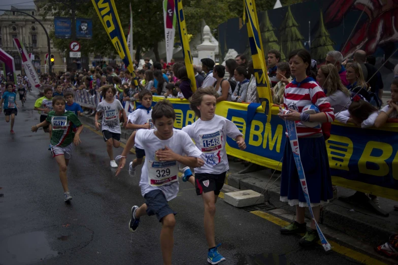 two boys running in a marathon with people watching