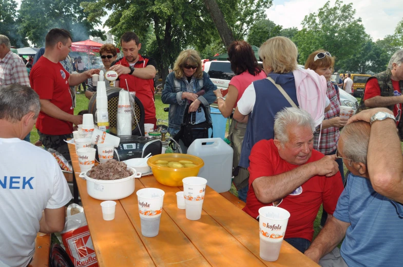 a group of people sit around an outside table with drinks and snacks