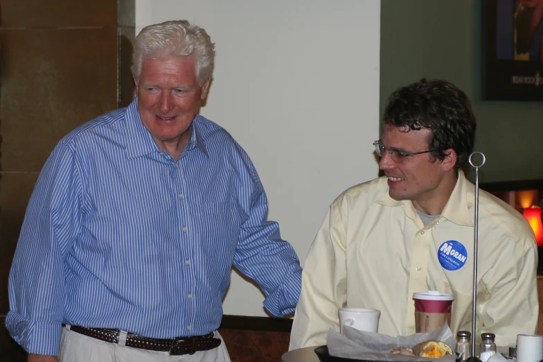 a man shaking another man's hand at a coffee house