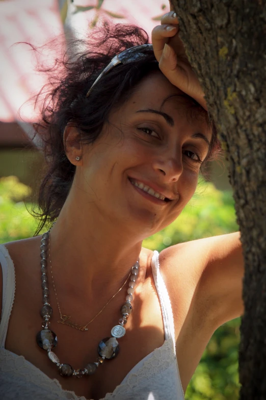 a woman smiling in front of a tree