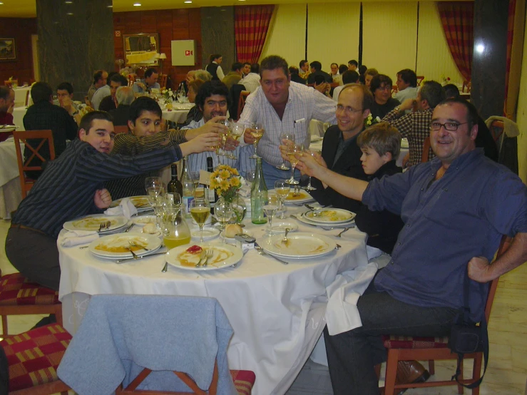 a group of people sitting at a table with plates and drinks
