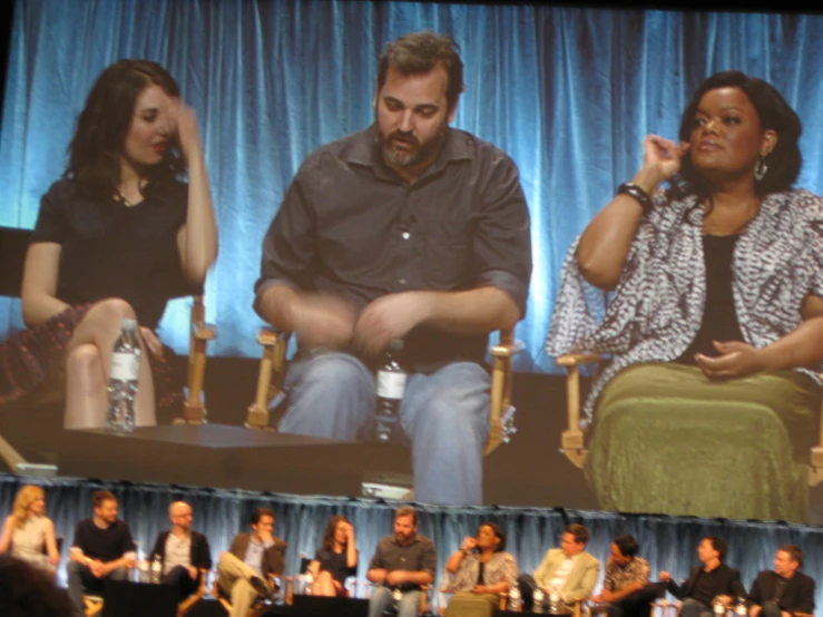 there are several people sitting at tables on a panel