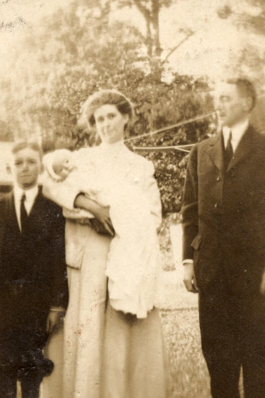 an old po shows a man and a woman standing near an older man and holding a baby