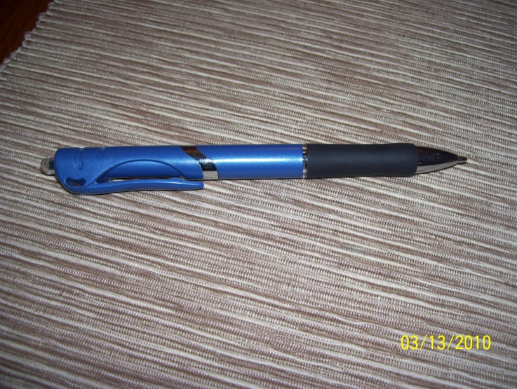 a blue plastic pen with black rubber tip on the bed