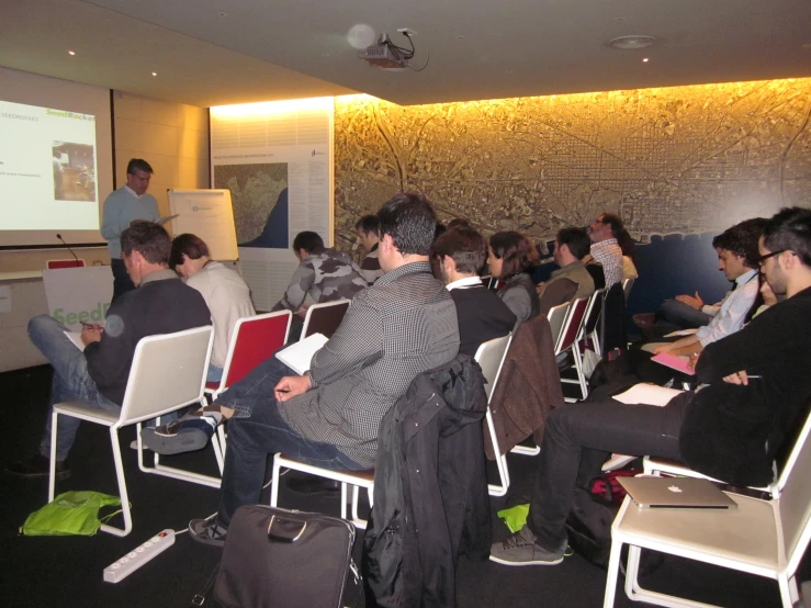 a group of people sitting in chairs watching a presentation