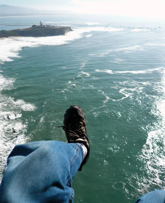 a pair of legs, with one foot propped on the edge of a pier