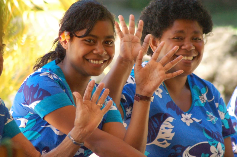 four young women in blue t - shirts are smiling and clapping