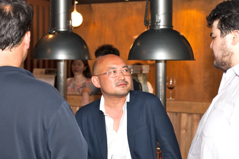 three men are talking to each other in front of lamp lights