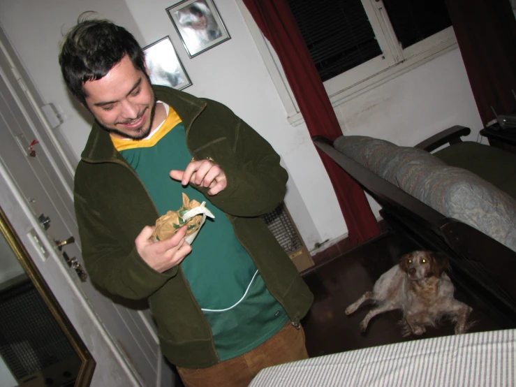 a man in a jacket is eating while a dog sits nearby