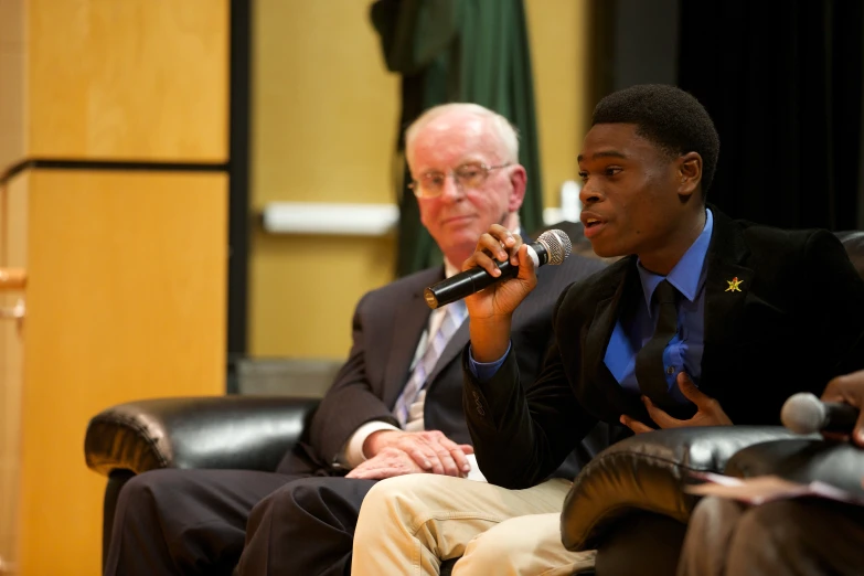 two men sitting in chairs talking into microphones