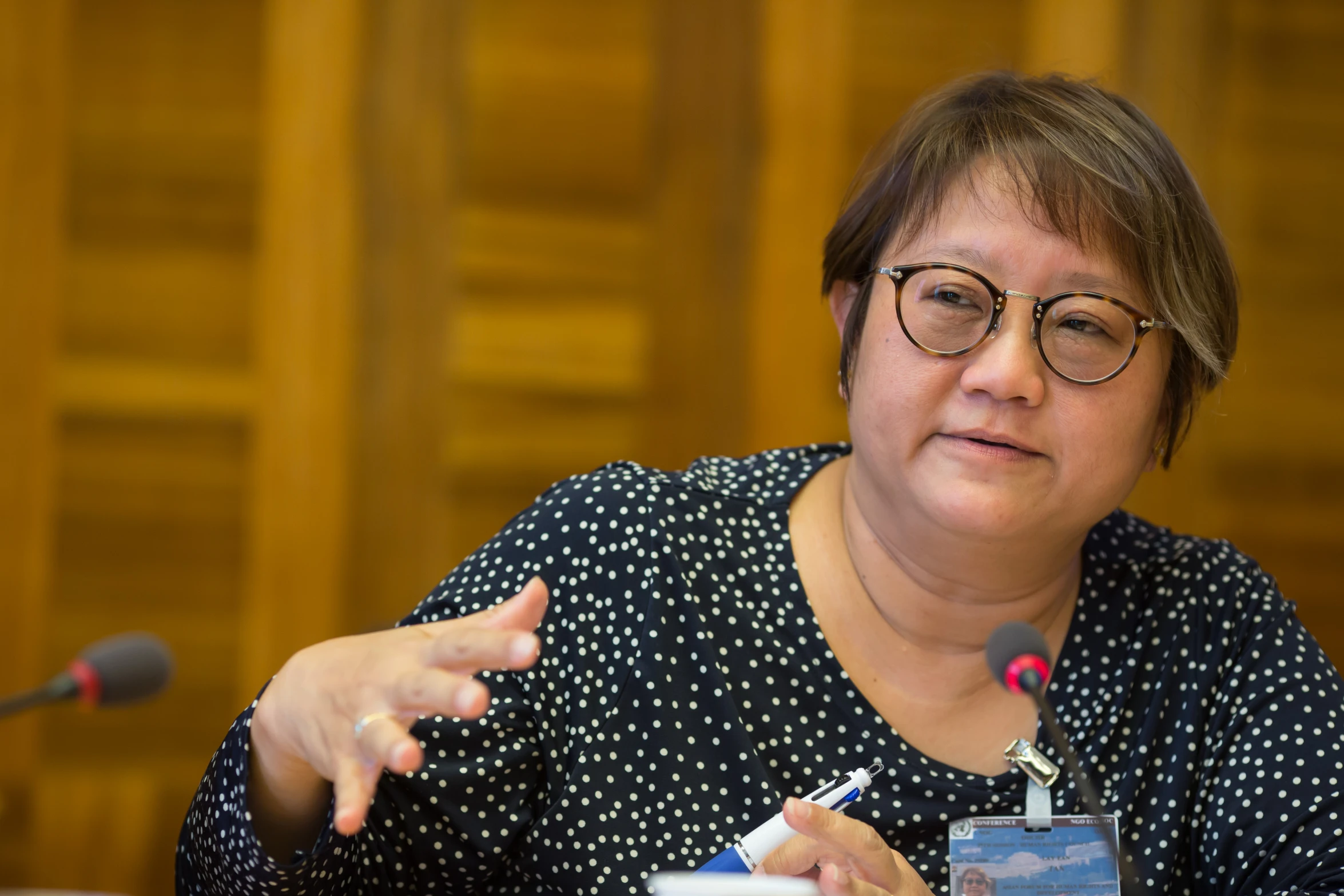 a woman sits in front of microphone and points