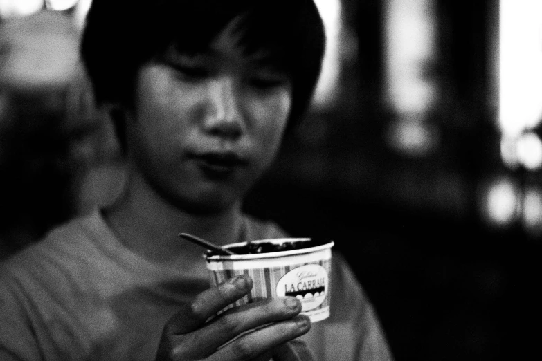 a person eating from a paper cup with a spoon