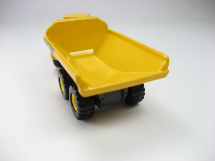 toy tractor with yellow container on white surface