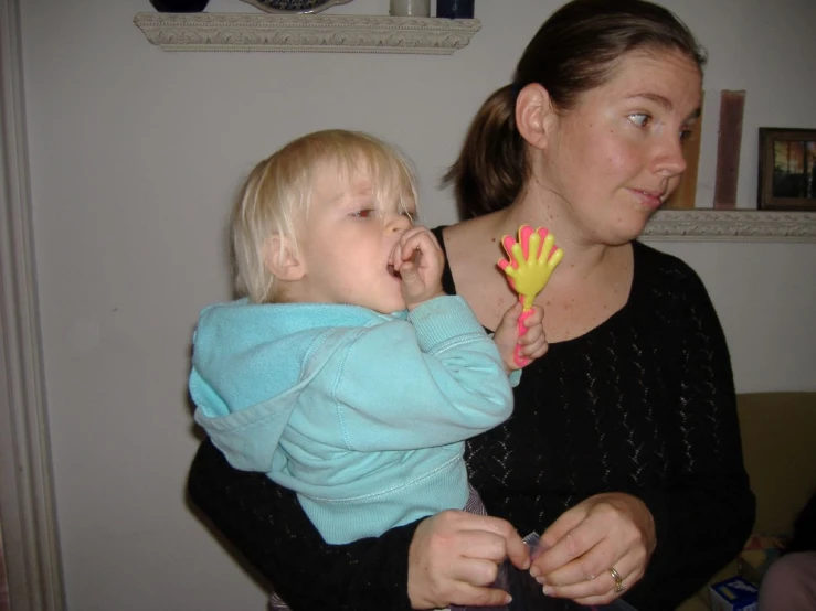 a woman holding a baby and playing with some plastic flowers