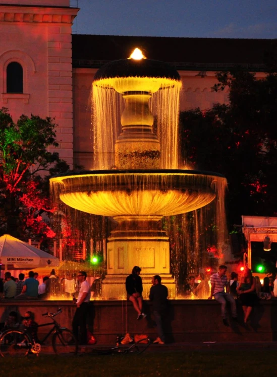 a fountain on a city street with people standing next to it