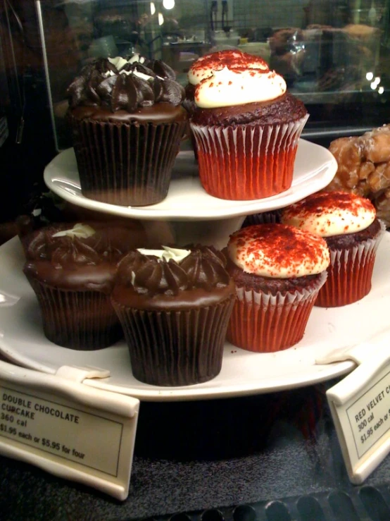 cupcakes sit on a three tiered tray with chocolate frosting