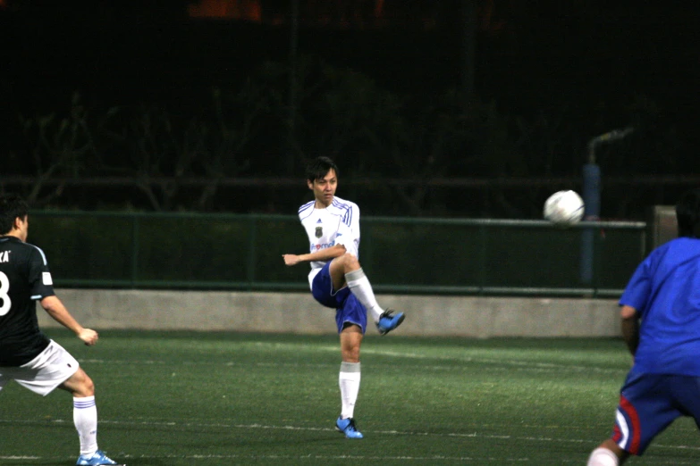 two soccer players kicking a soccer ball in the air