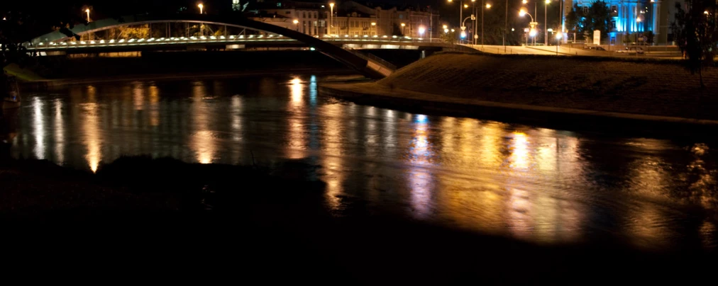 the lights on the street are reflected in the river