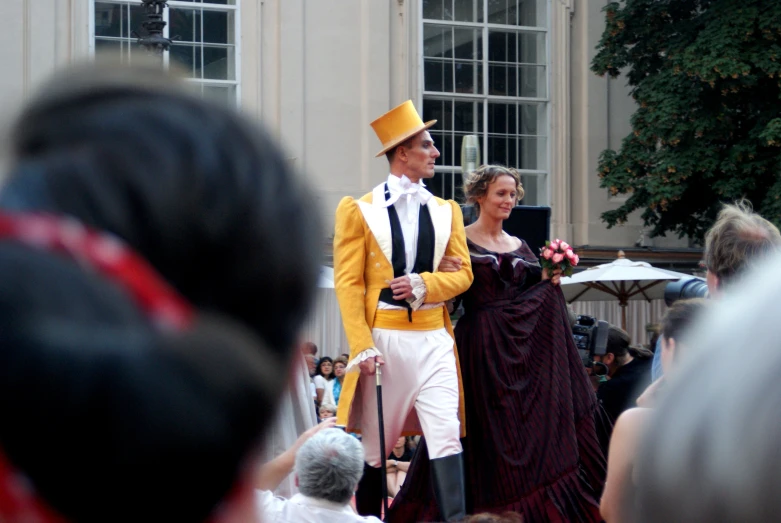 a man and a woman walking in front of a crowd