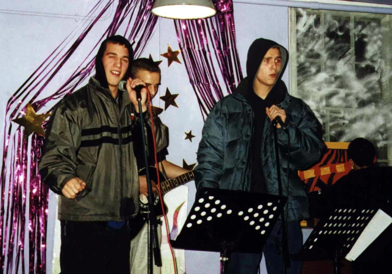 a group of young people singing in front of microphones