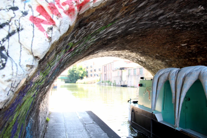 graffiti is painted on the side of the bridge as people walk under it