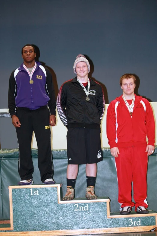 a group of three people standing on top of a wooden podium