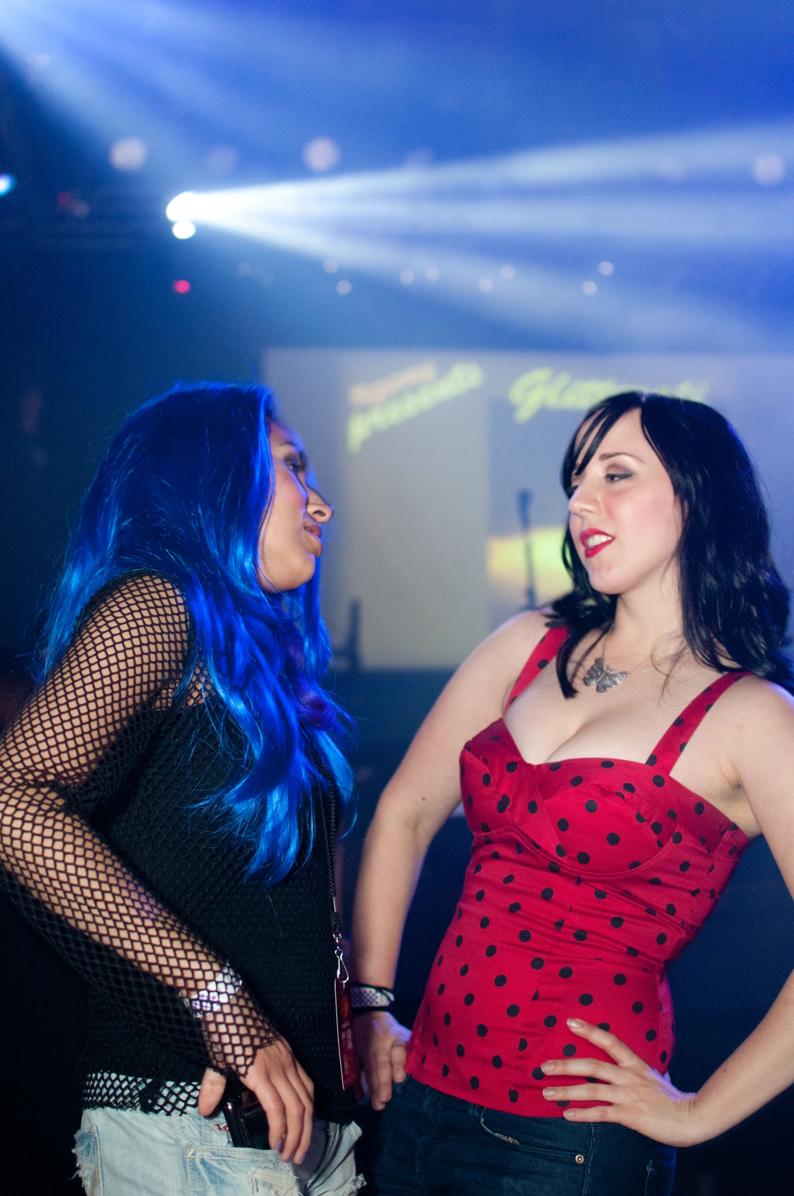 two women are talking and laughing in a crowded room