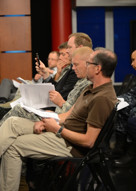 men sit in chairs and look at papers