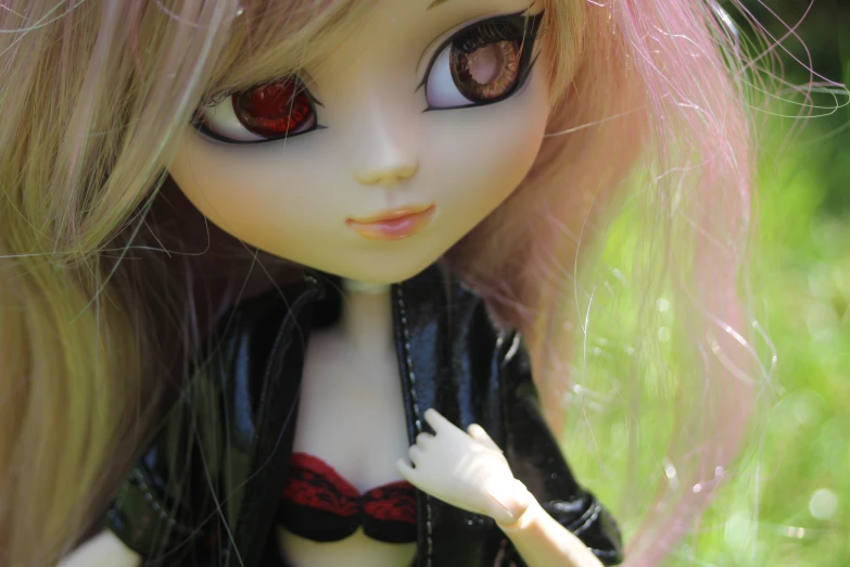 a girl doll in leather clothes standing next to a grass covered field