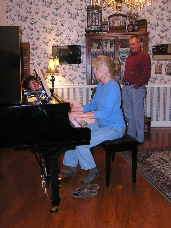 a woman is playing a grand piano and a man watches