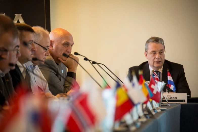 two men sitting at a table during a press conference